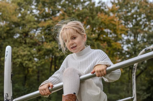 Kind speelt op een klimrek in een bosrijke omgeving